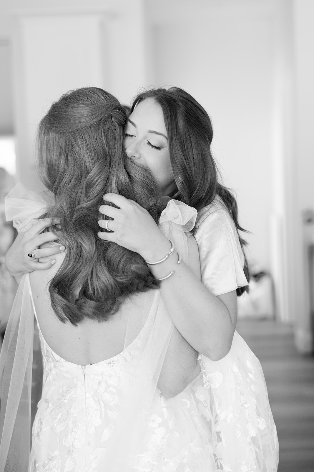 Bride embracing her bridesmaid in a heartfelt hug before the ceremony, a candid moment captured by a Greenville wedding photographer.