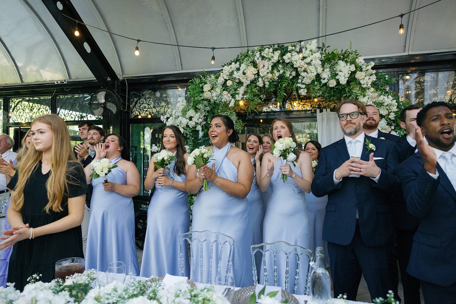 Bridesmaids and groomsmen stand and cheer as the couple makes their entrance.