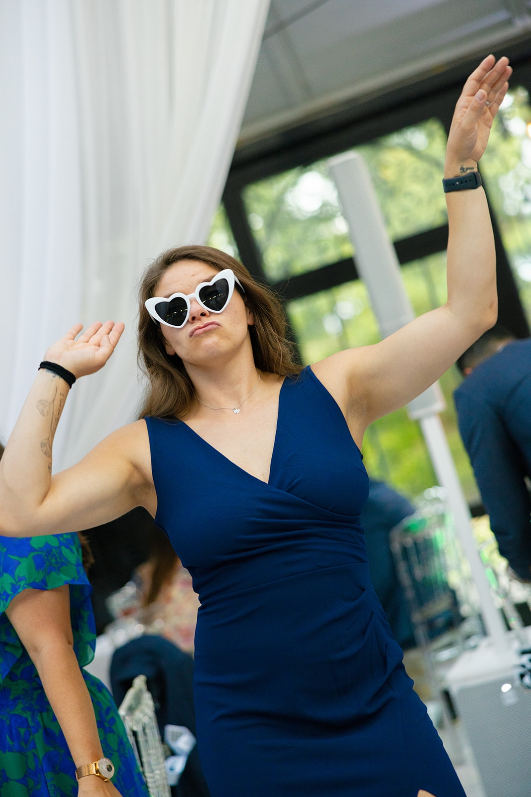 Guest in blue dress dances with heart-shaped sunglasses 