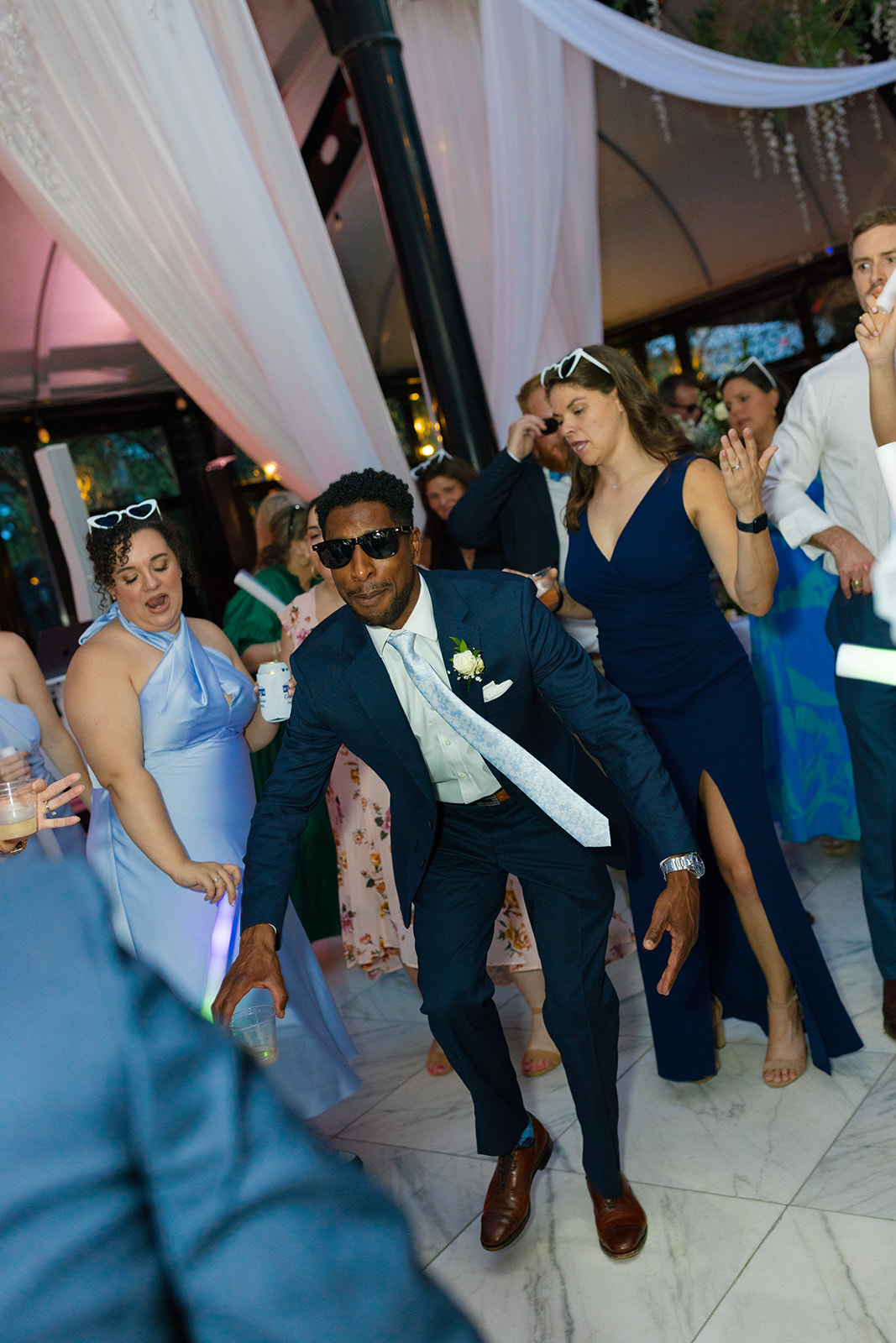 Wedding guest in a navy suit and sunglasses dancing on the dance floor at Edinburgh West