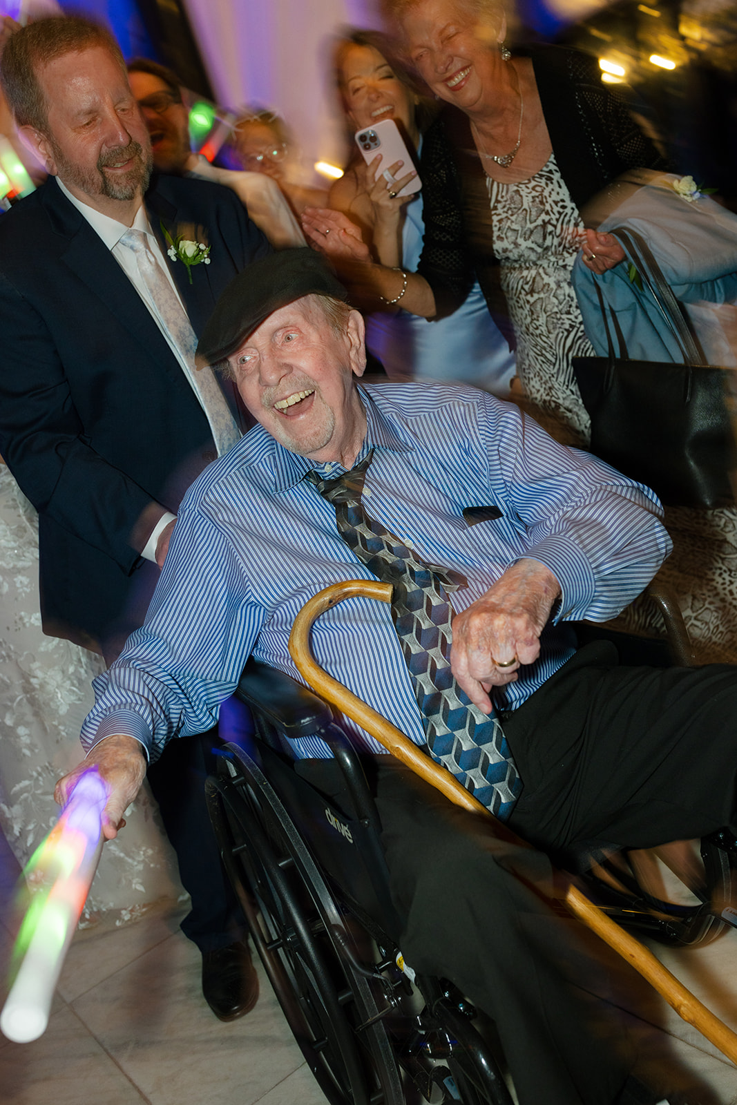 Elderly guest enjoying the wedding reception in Greenville, SC, waving a glow stick while surrounded by smiling family
