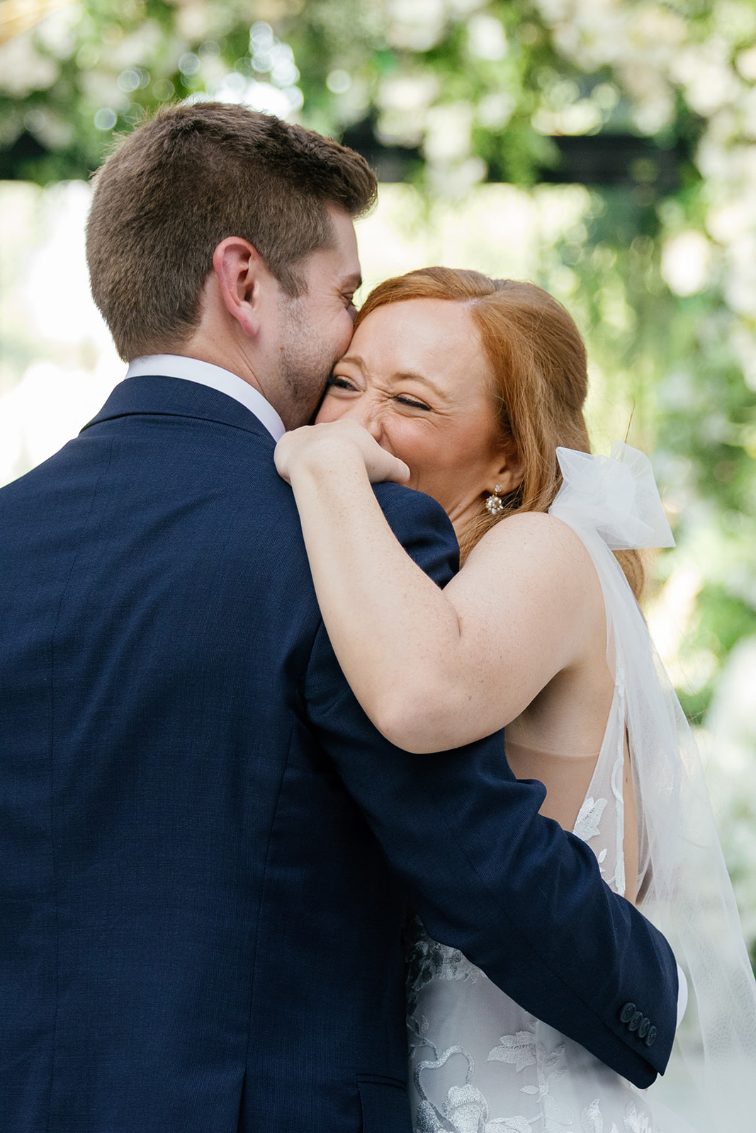 Close-up of bride laughing joyfully in the groom’s arms during their first dance.