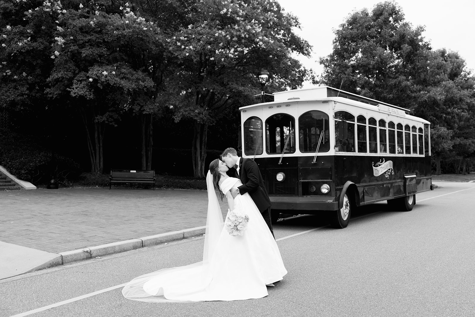 Groom kisses bride as he dips her in front of a trolley