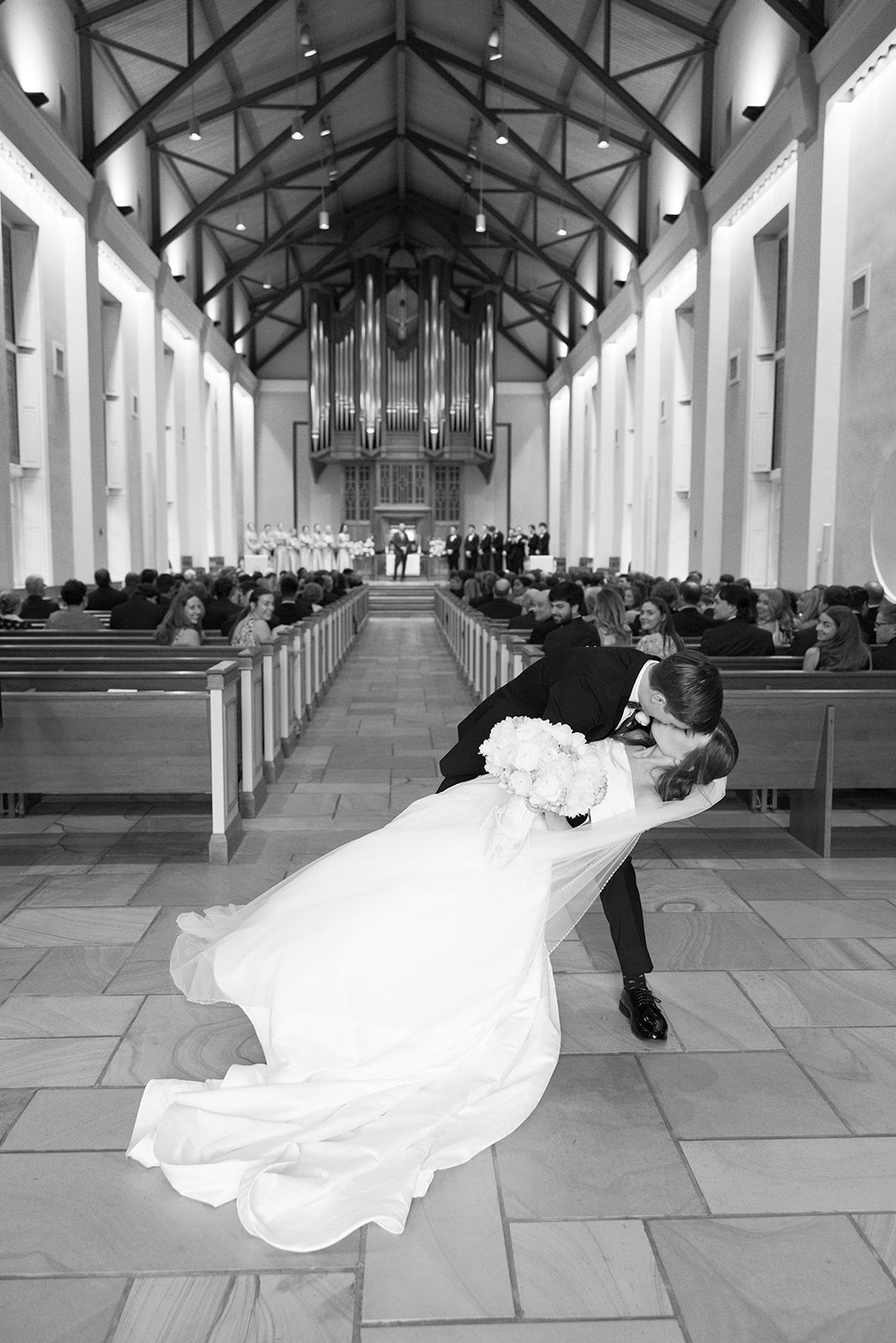 Bride and groom share a kiss in the aisle at Daniel Chapel at Furman University