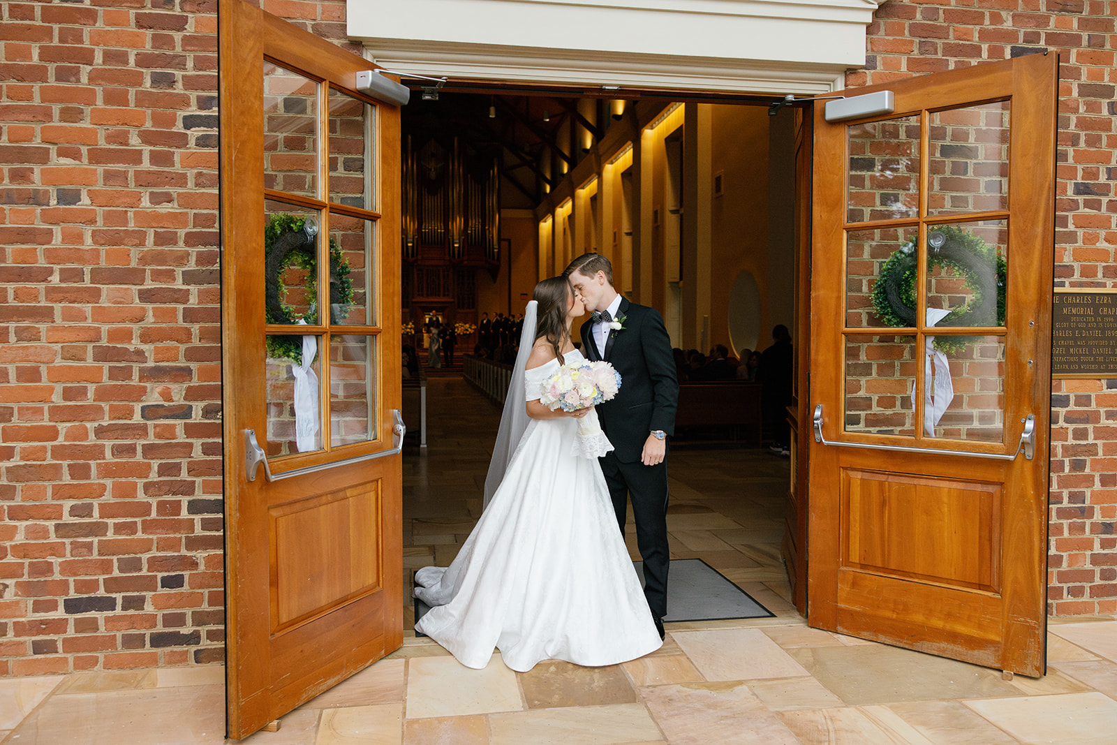 Bride and groom share a kiss in the doorway of Daniel Chapel at Furman University