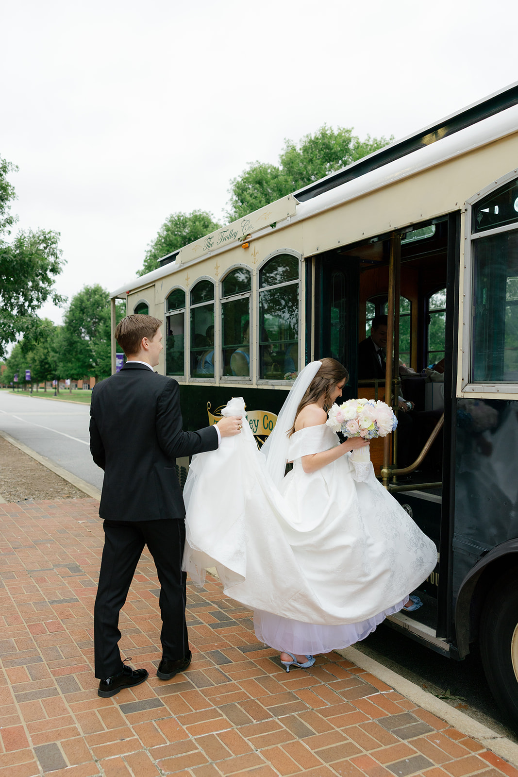 Groom holds bride's dress as she boards the trolley to their South Carolina wedding reception