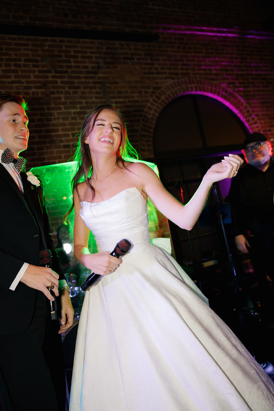 Groom sings with energy and joy as he performs on stage, surrounded by guests and the live wedding band.