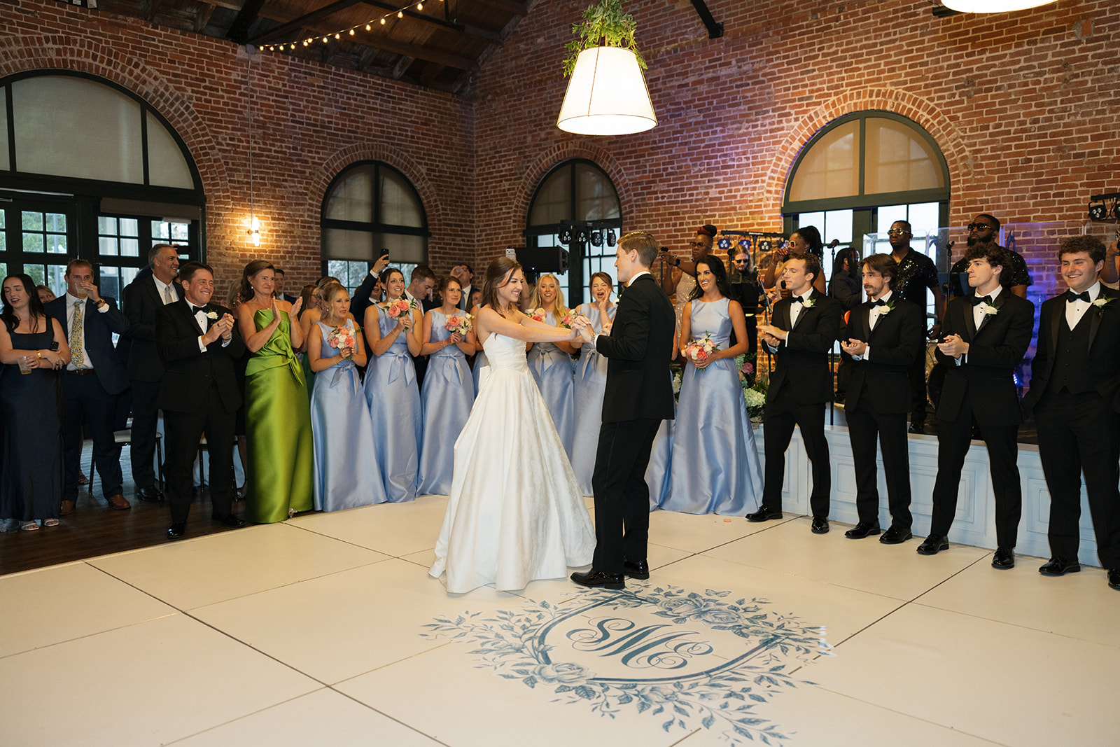 Newlyweds share their first dance as  bridesmaids and groomsmen cheer them on