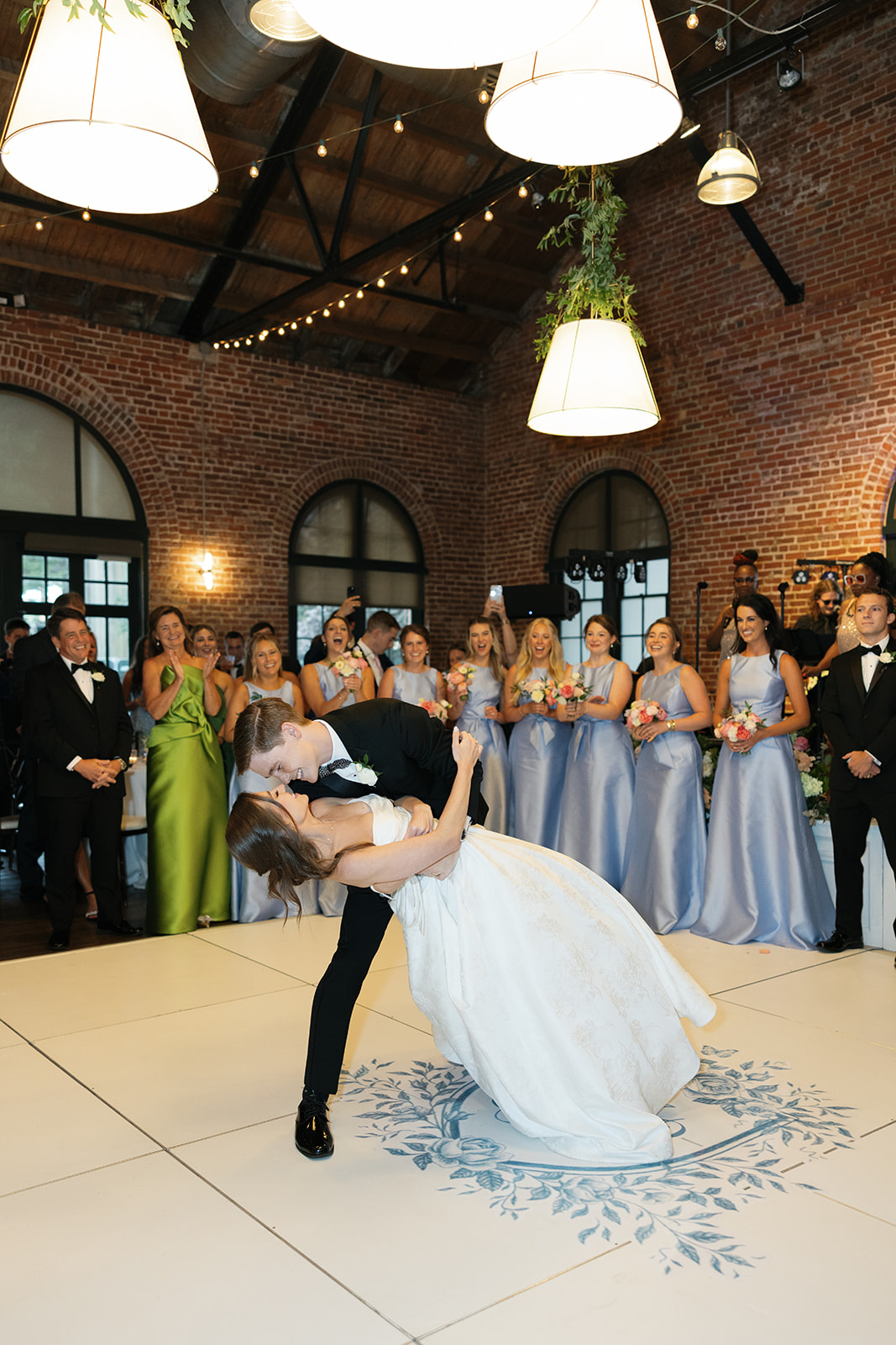 Newlyweds share their first dance as  bridesmaids and groomsmen cheer them on