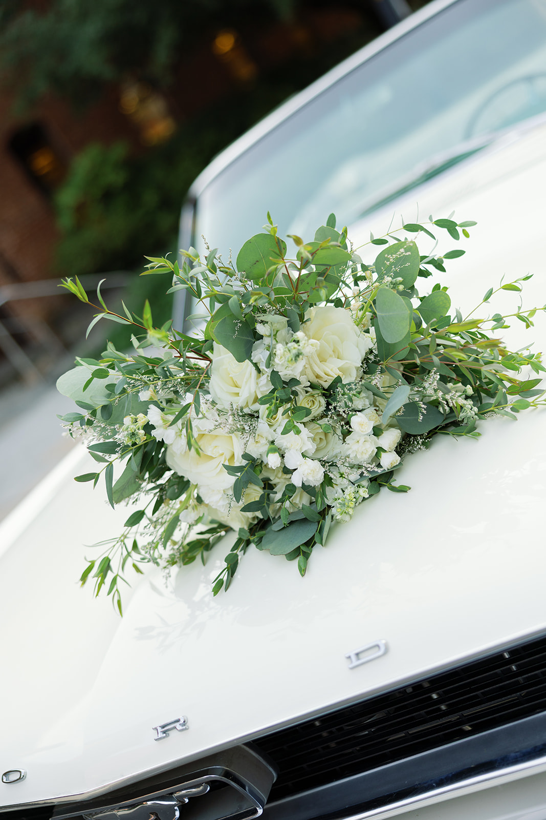 the bride's bouquet on top of their classic car
