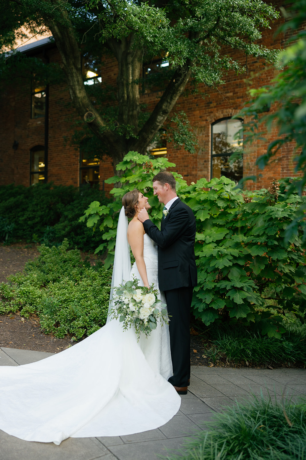 the groom holding the bride's face as they look at each other 