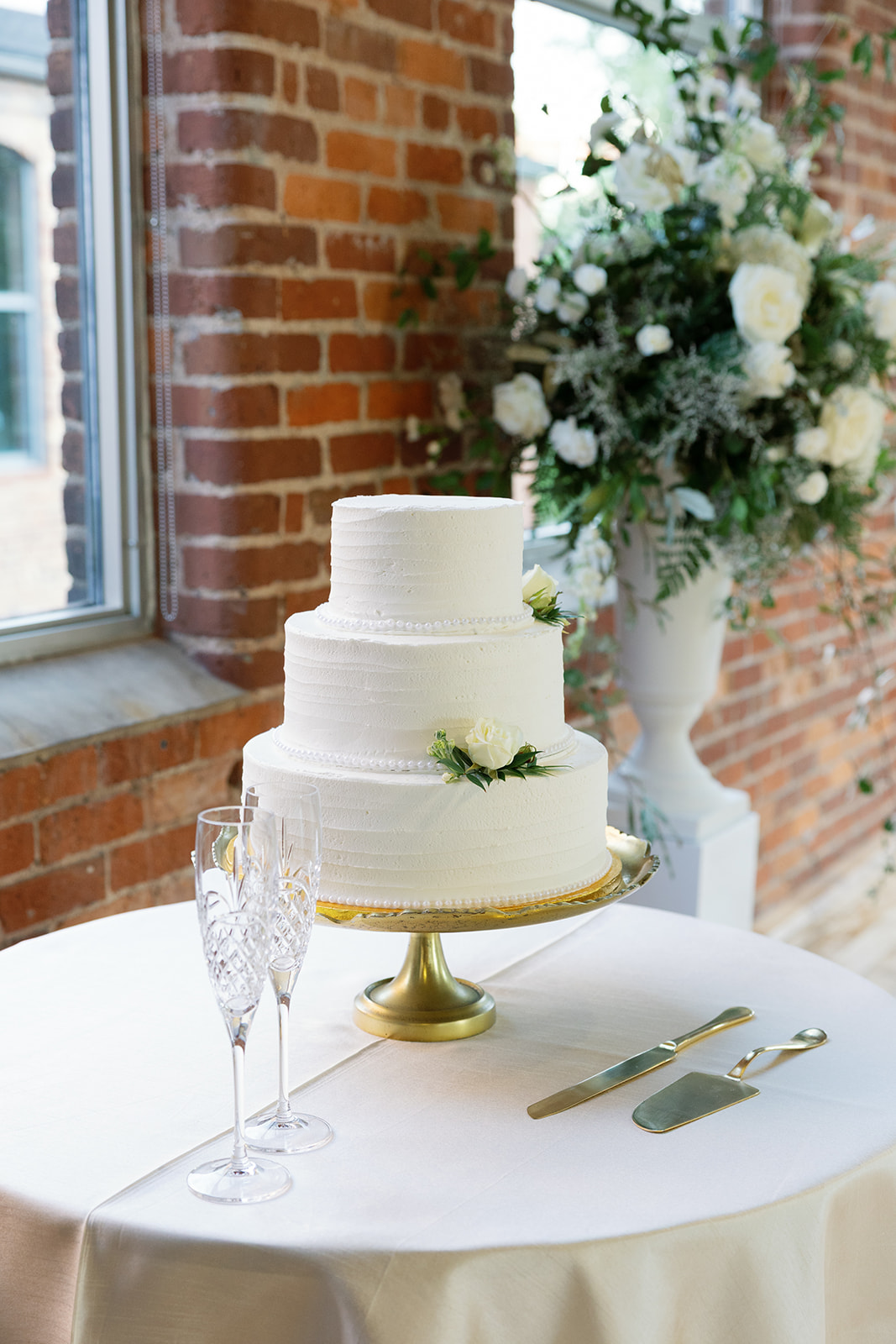 3 tiered white cake on a gold cake stand 