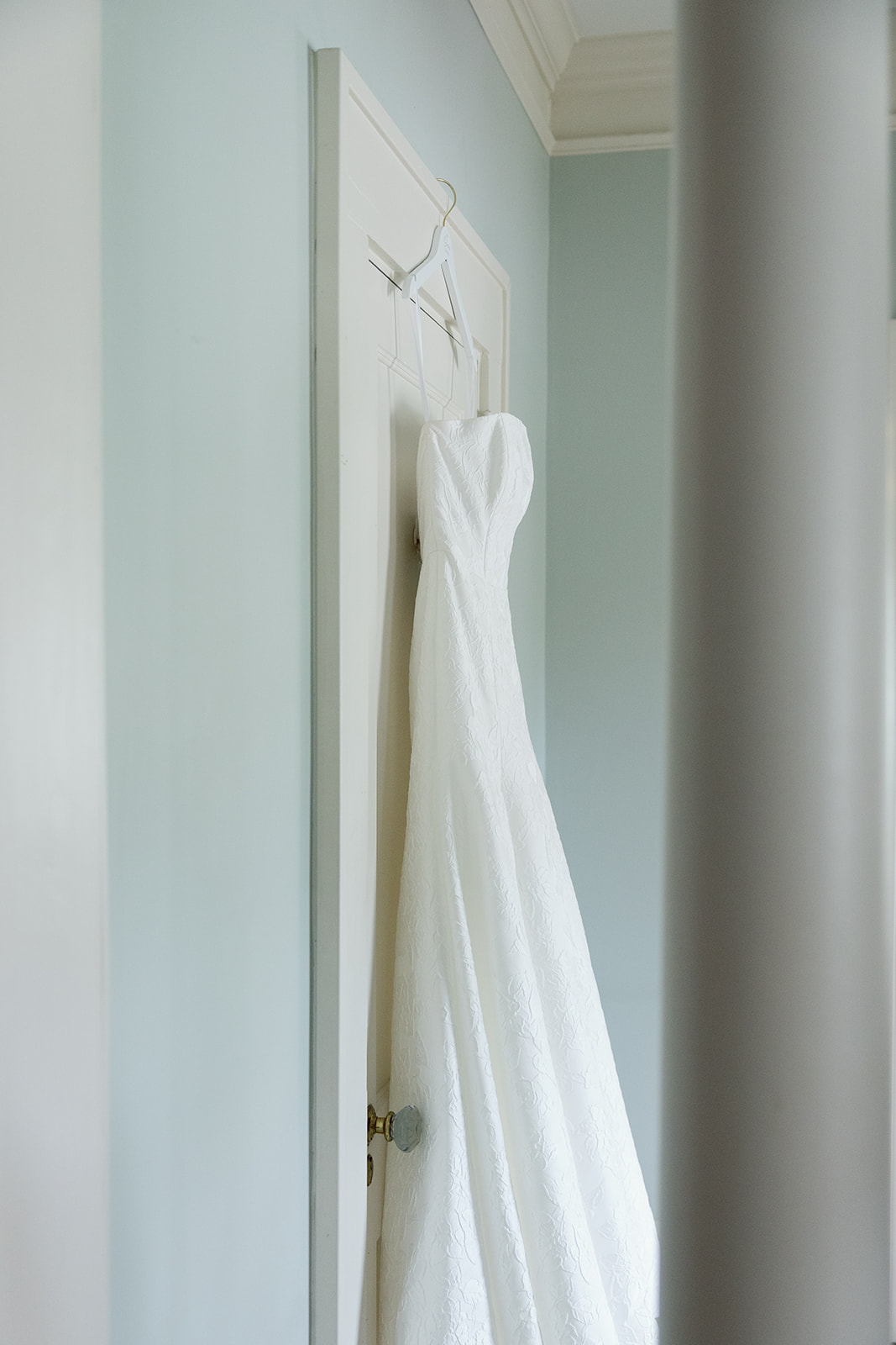 the bride's wedding dress hanging on a door during a Wedding Photography Timeline