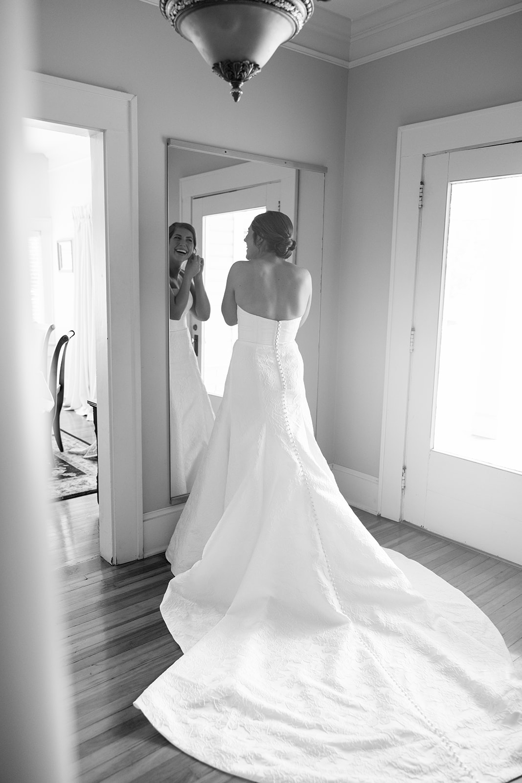 the bride smiling into a mirror as she puts on her earrings 