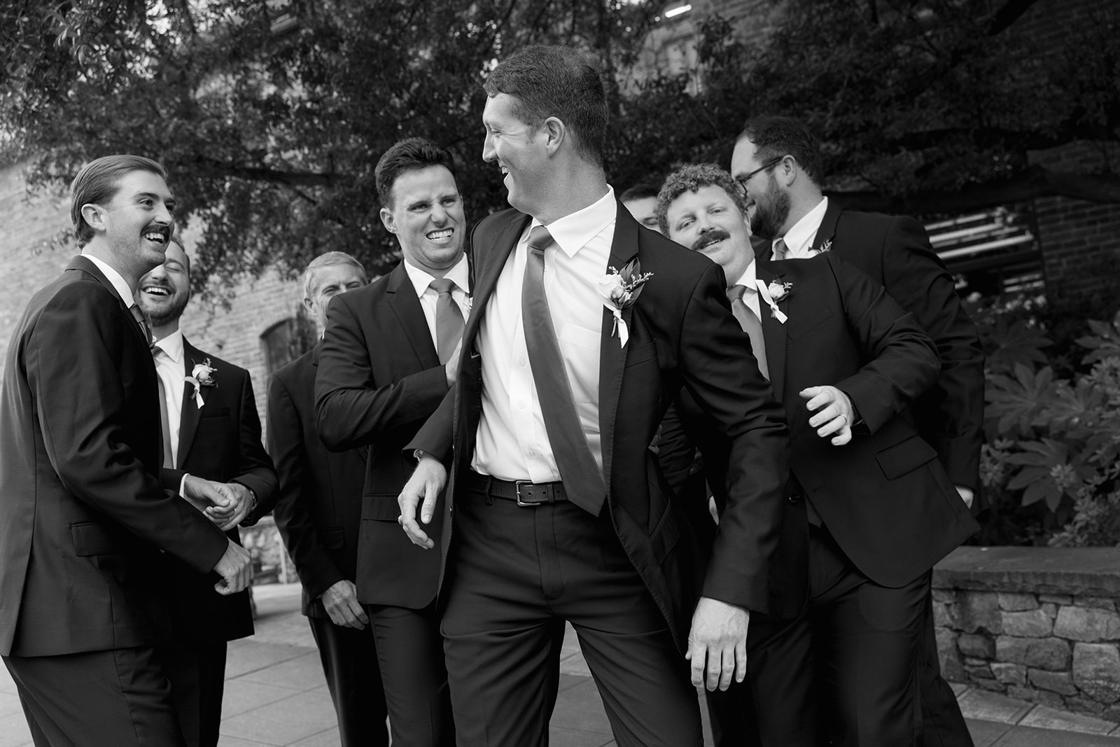 a candid photo of the groom and his groomsmen playing around during portraits in Greenville 