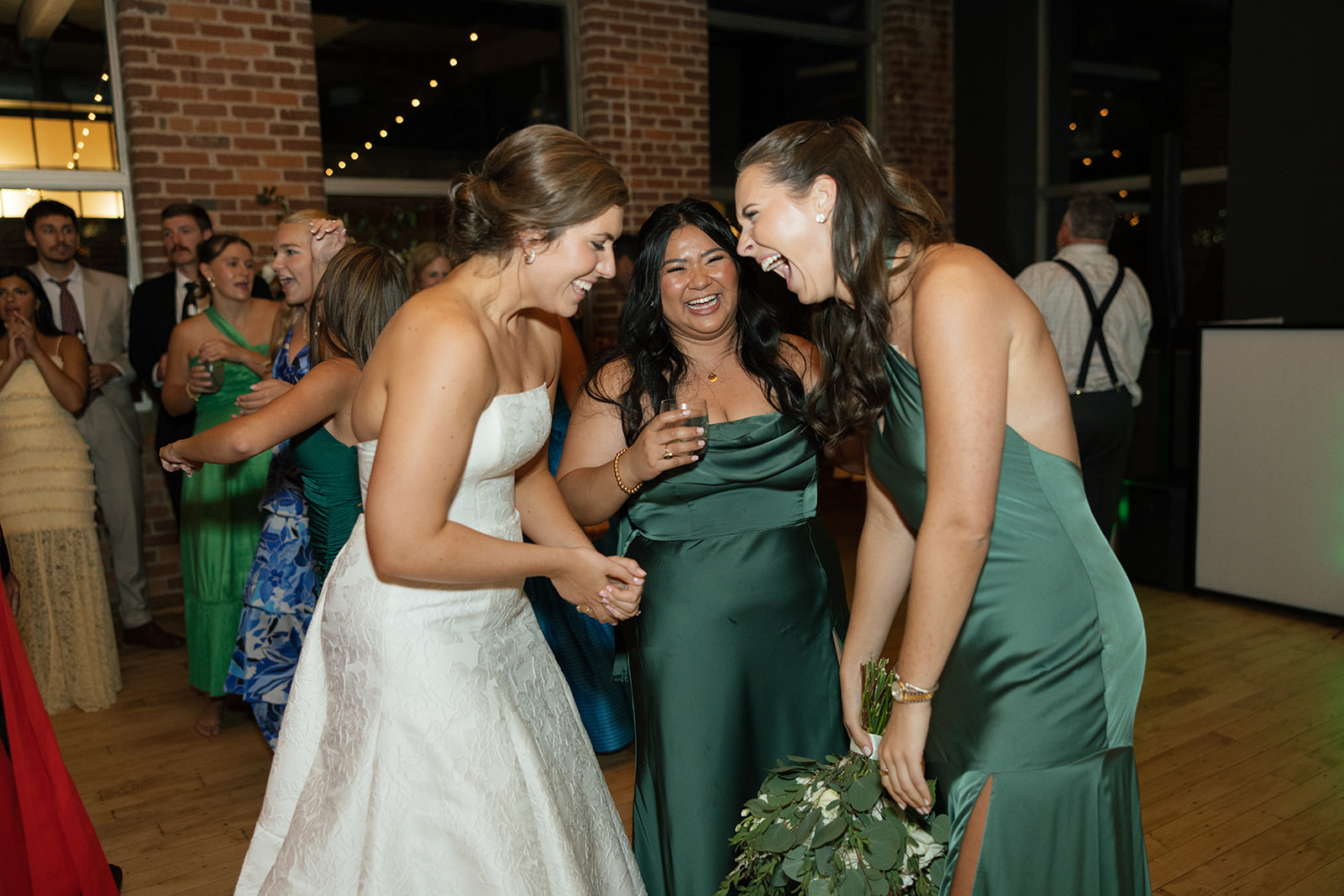 the bride laughing with her bridesmaids after they caught her bouquet 