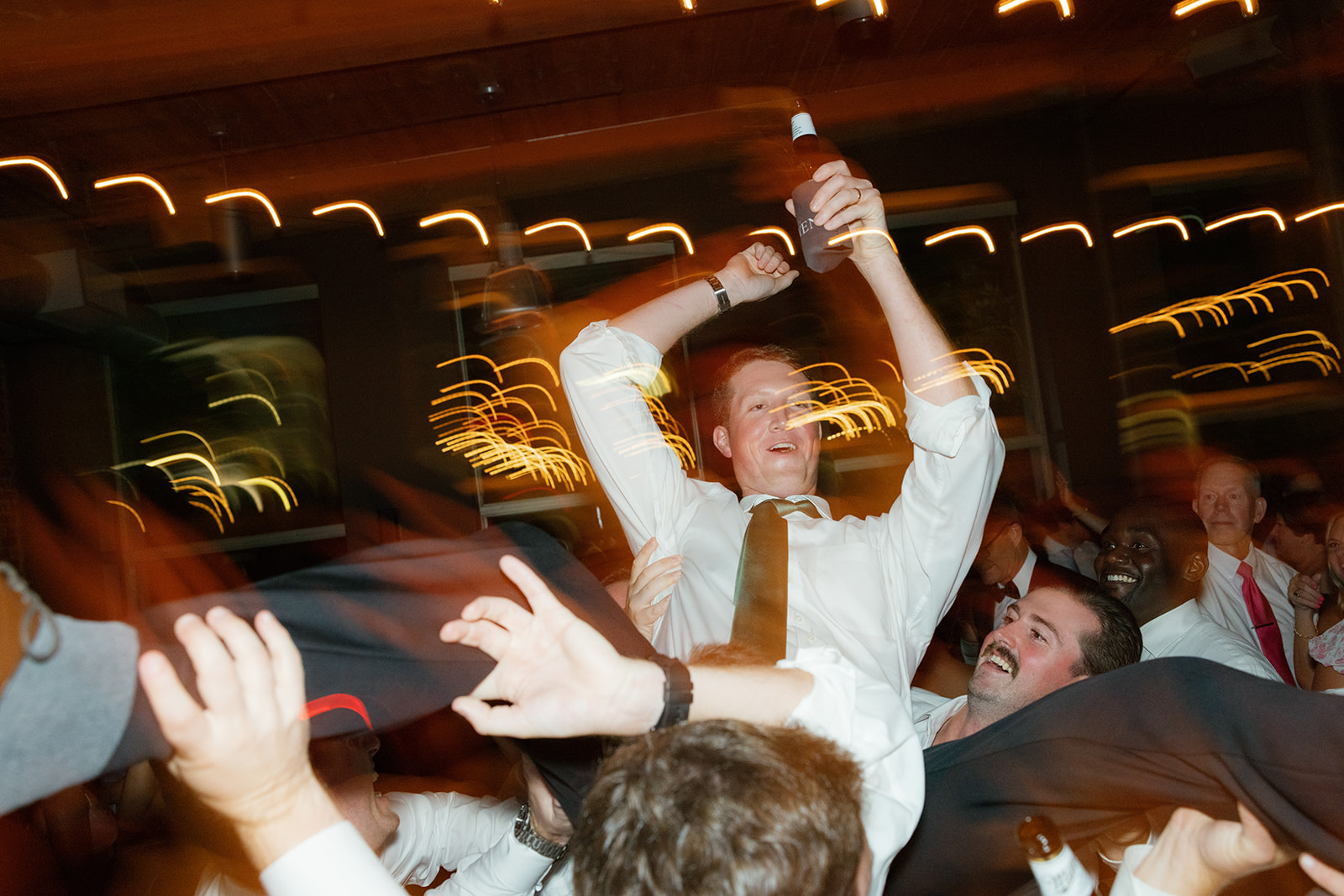the groom being lifted up in the air at their Greenville Wedding reception