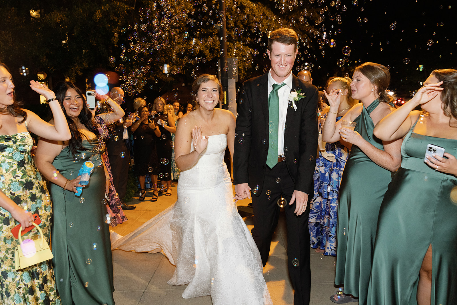 the bride and groom walking through a bubble exit during this portion of the Greenville Wedding Photography Timeline