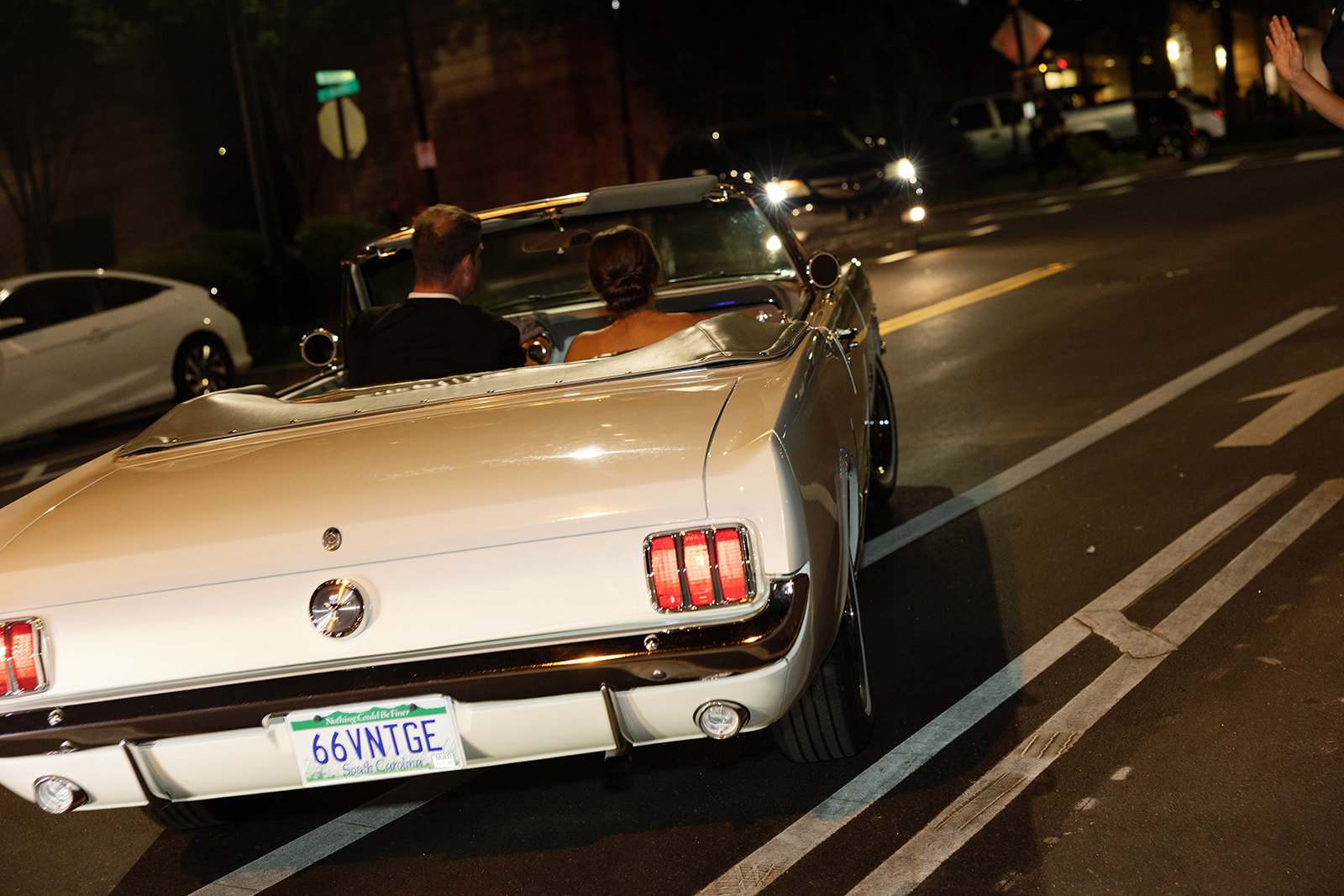 the bride and groom driving off in their classic car 